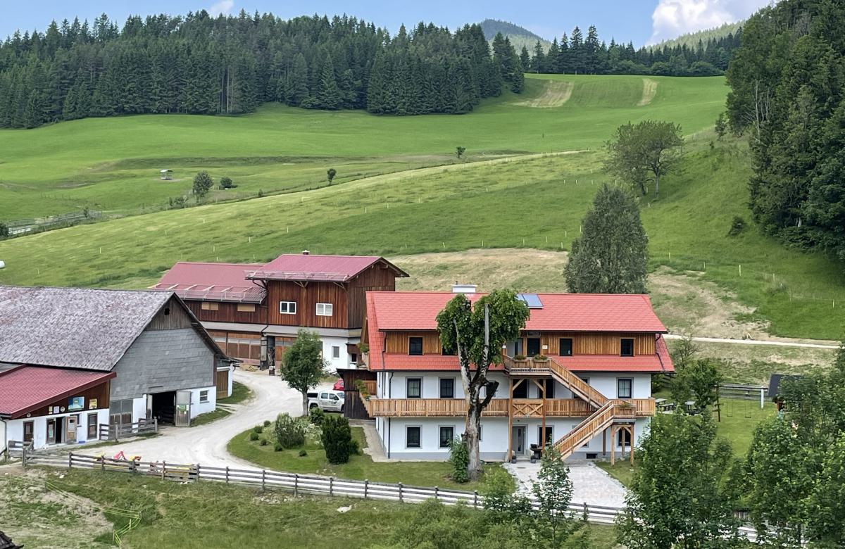 Bio-Bauernhof Poldlbauer mit Wohnhaus und Hofgebäuden, umgeben von Wiesen und Wald.